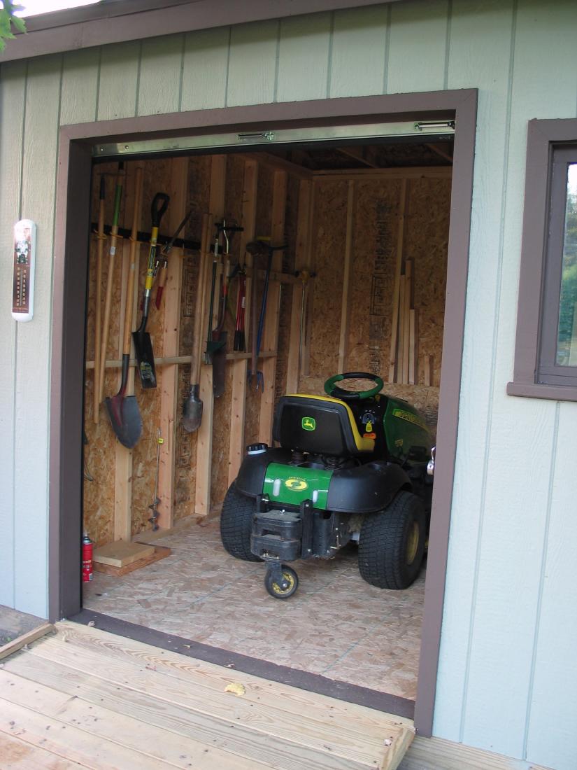 Insidethe Shed
Here's a view with the door open.  We added some hanging storage for long-handled tools to the left of the tractor.  Eventually we will add shelving in front of the tractor as well.

