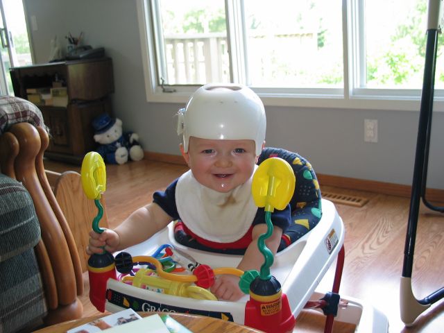 Walking, thanks to my Walker
William in his walker, which he loves to explore the living room, dining room, and kitchen in.  What's the helmet about?  It's a CranioCap which is helping round out the back of his head, which was flattened at a young age by him preferring to lay in the same position.
